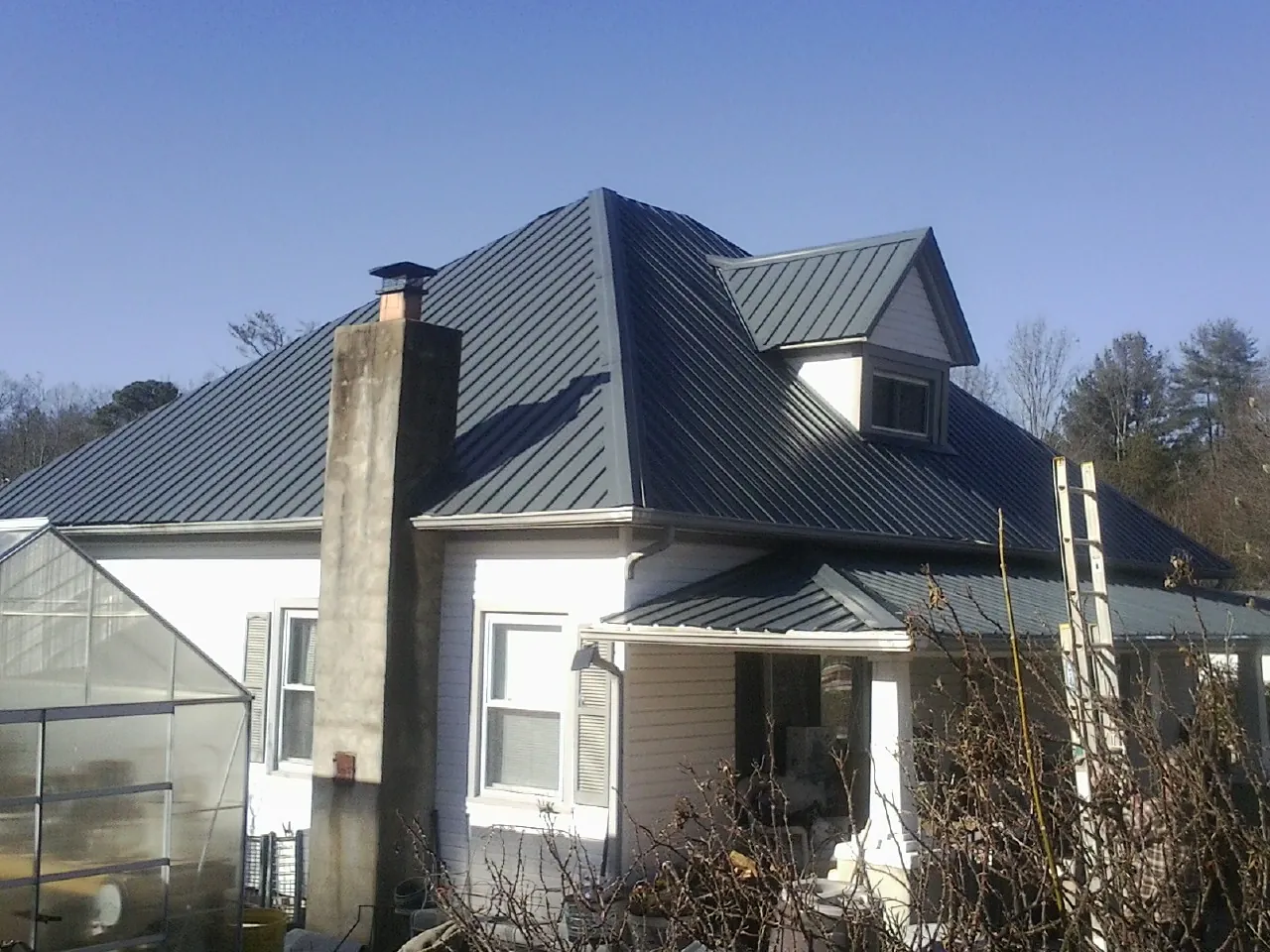 Dark blue standing seam metal roof on a white farmhouse with dormer — Slate & Tile Roof Repair by Roofing Brothers in Sperryville