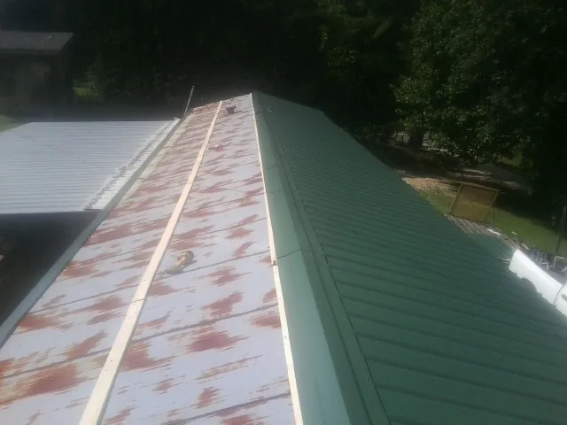 Old rusted panels beside newly installed green metal roofing — Wind Damage Roof Repair by Roofing Brothers in Sperryville