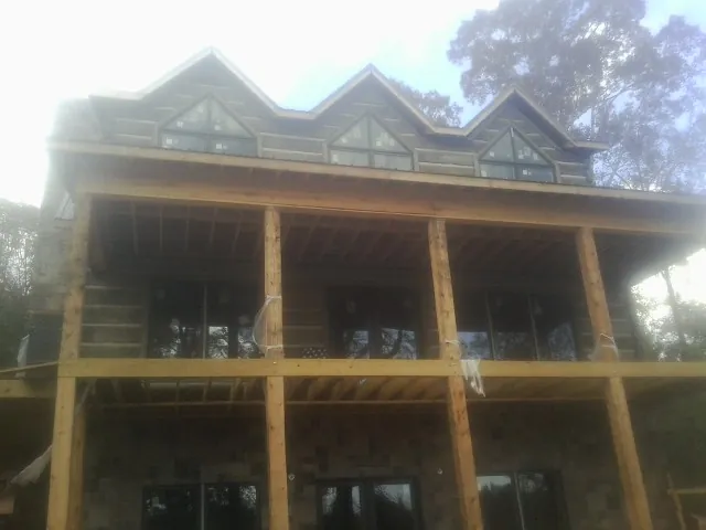 Dormers and porch framing on a large log home under construction — Roof Coating work by our crew in Sperryville