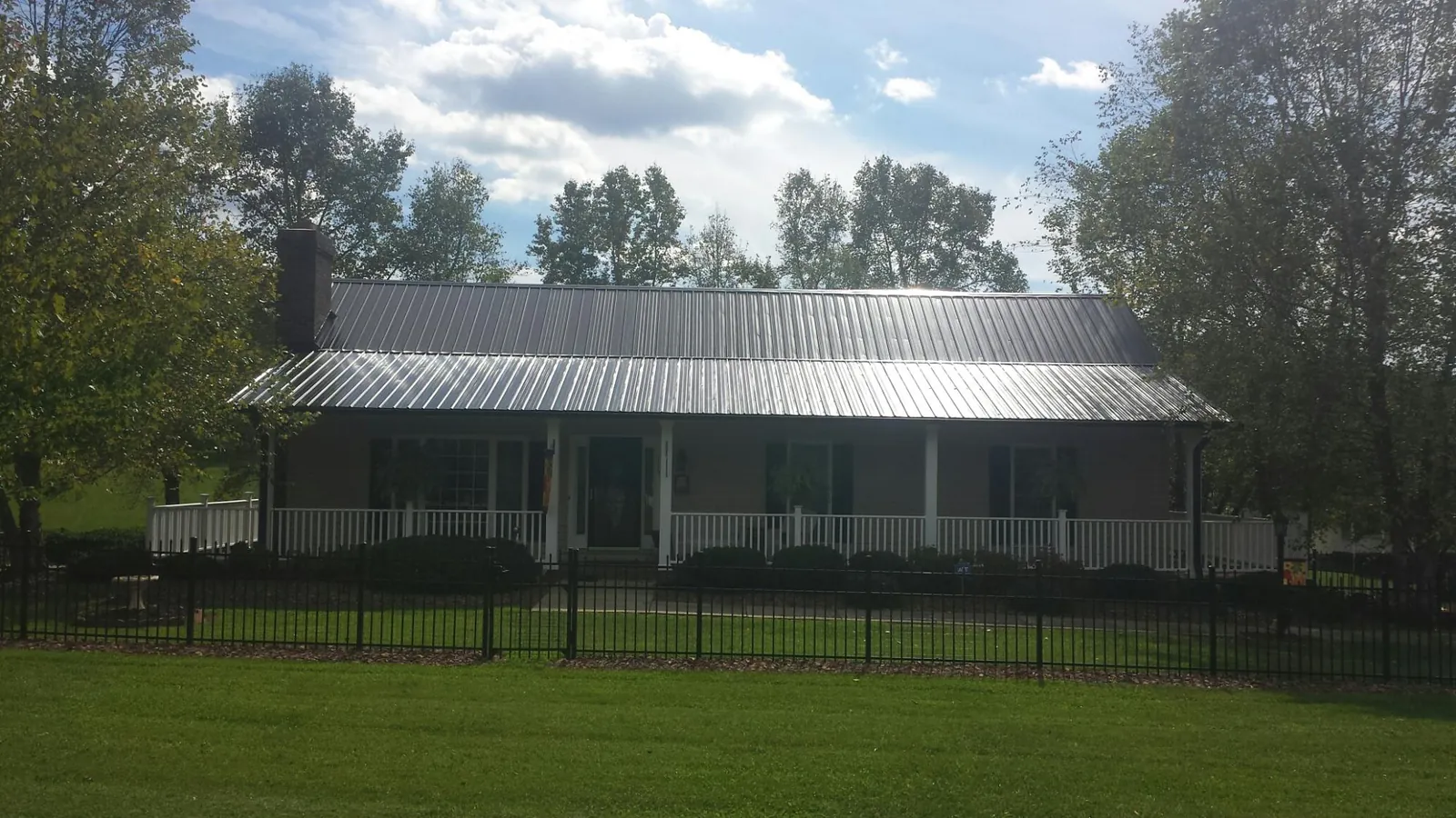 Gray metal roof on a brick ranch with a full width front porch — Gutter Guard Installation work by our crew in Sperryville