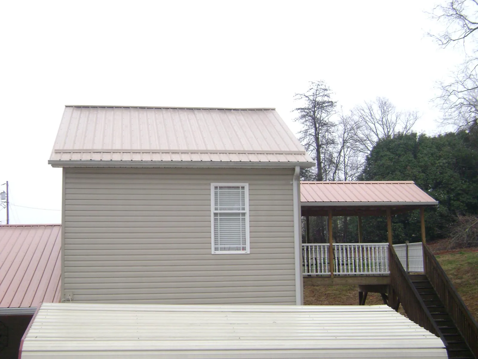 Tan metal roofs on a two story addition and attached porch, from a Roof Replacement job in Sperryville