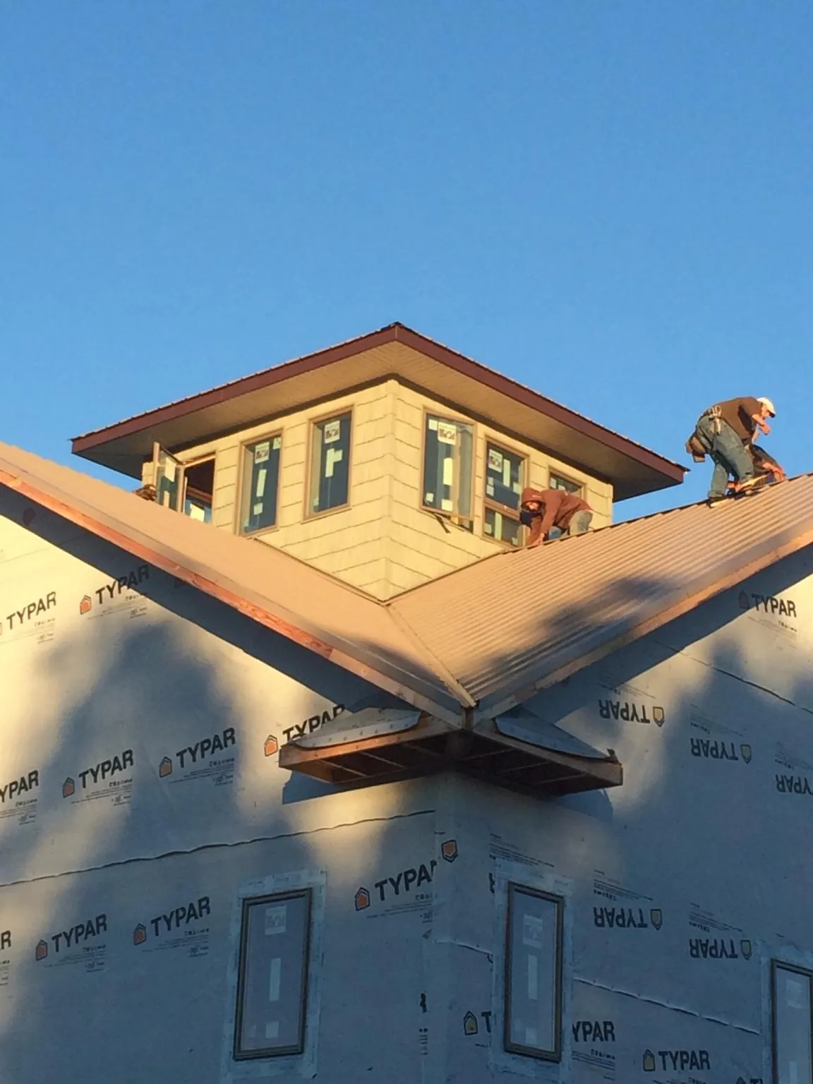 Roofers working around a rooftop cupola on a new metal roof at sunset — Roof Waterproofing in Sperryville by Roofing Brothers